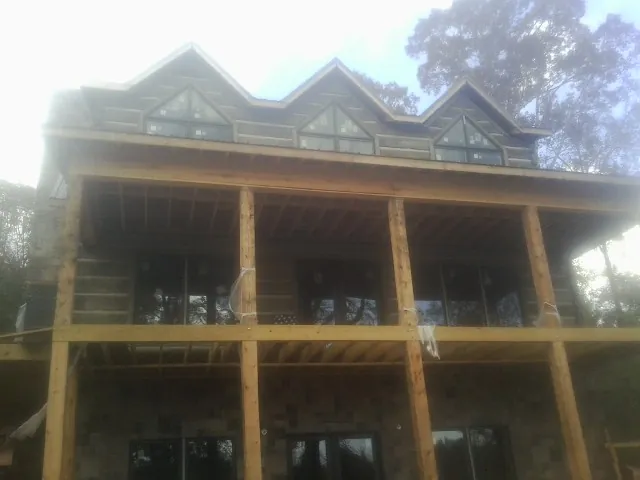 Dormers and porch framing on a large log home under construction — Roof Coating work by our crew in Acme