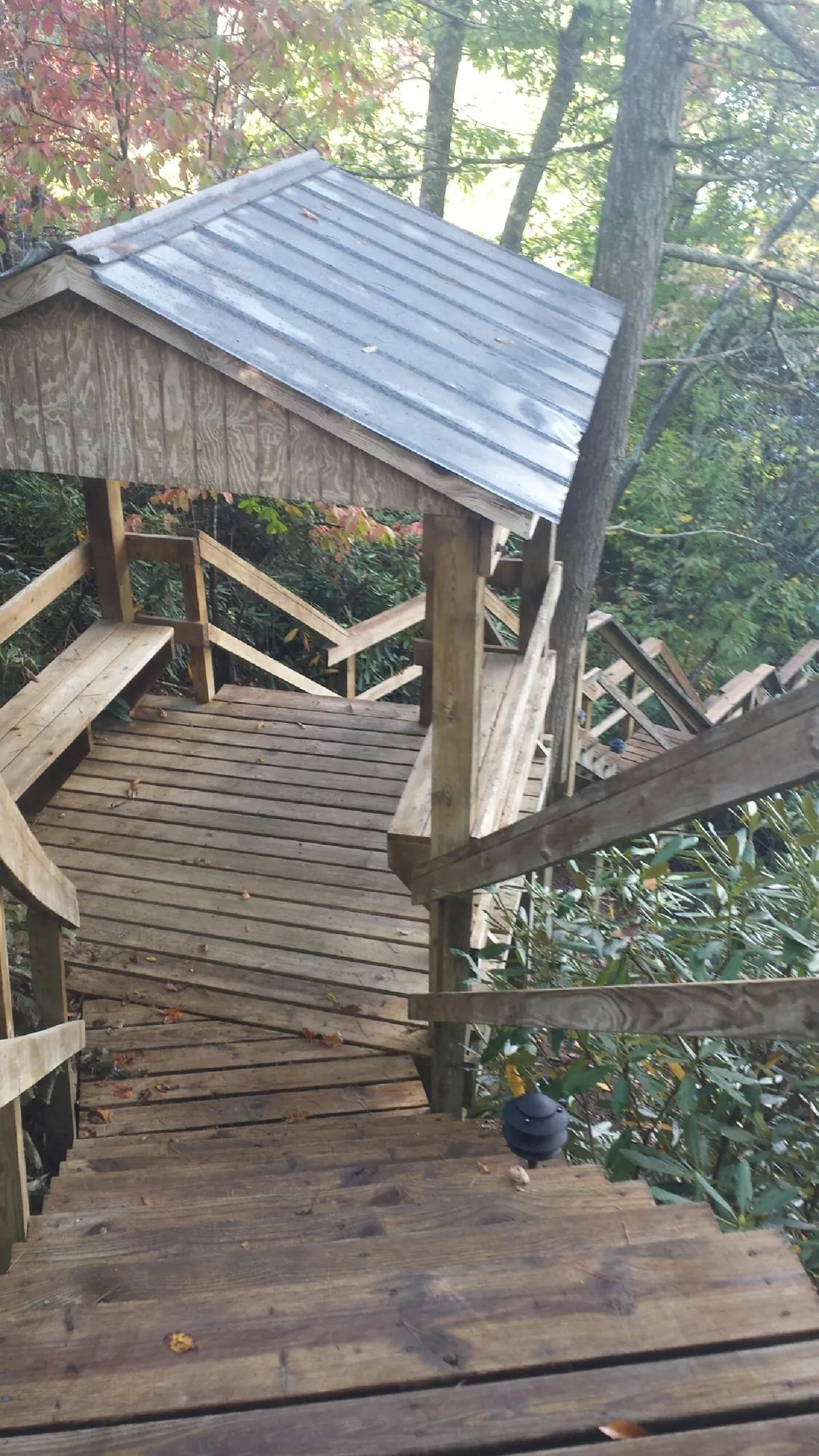 Metal roofed shelter over wooden steps on a wooded walkway — Skylight Repair & Installation work by our crew in Acme